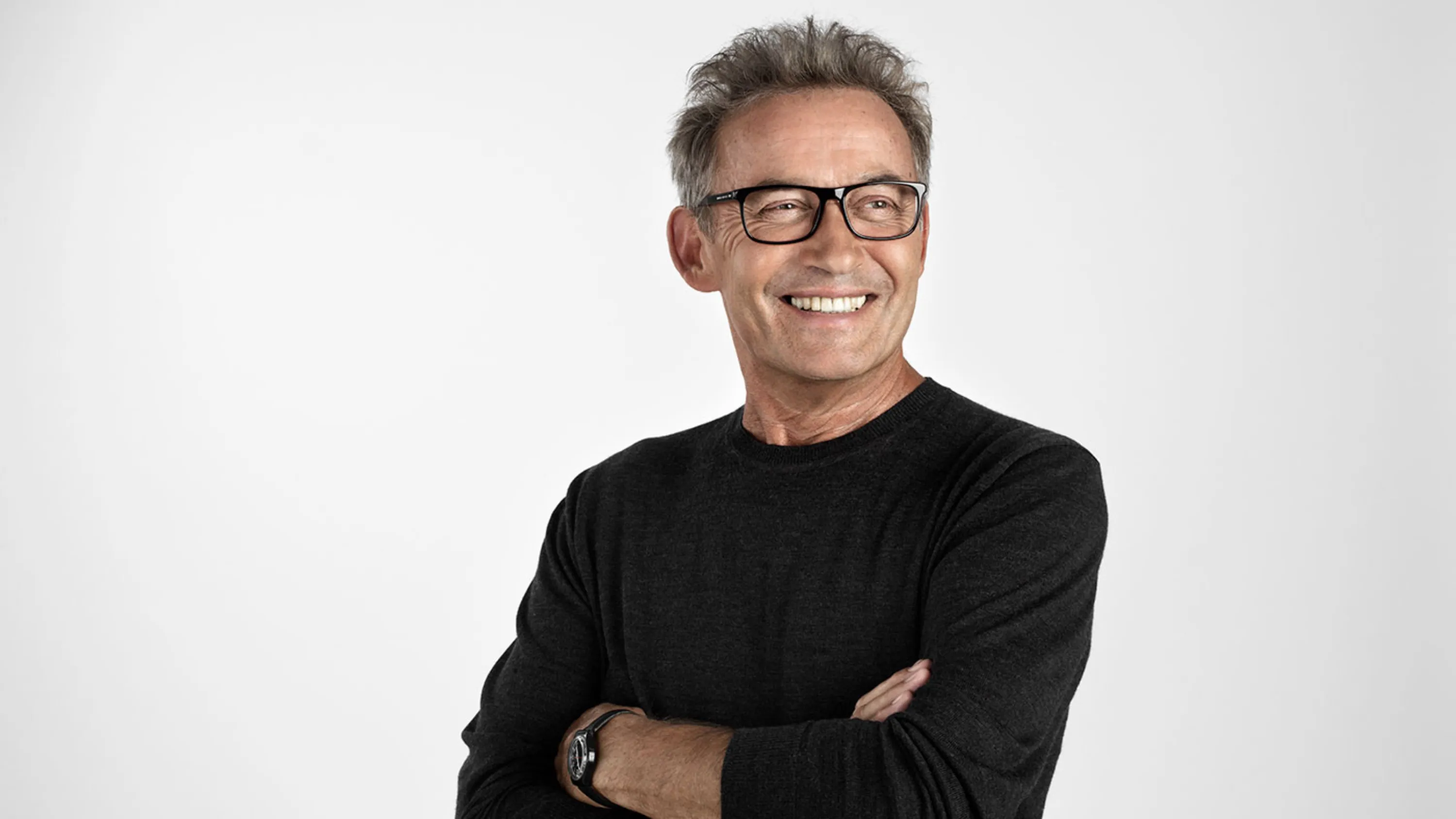 Porträt eines grau melierten, lachenden Mannes mit Brille.