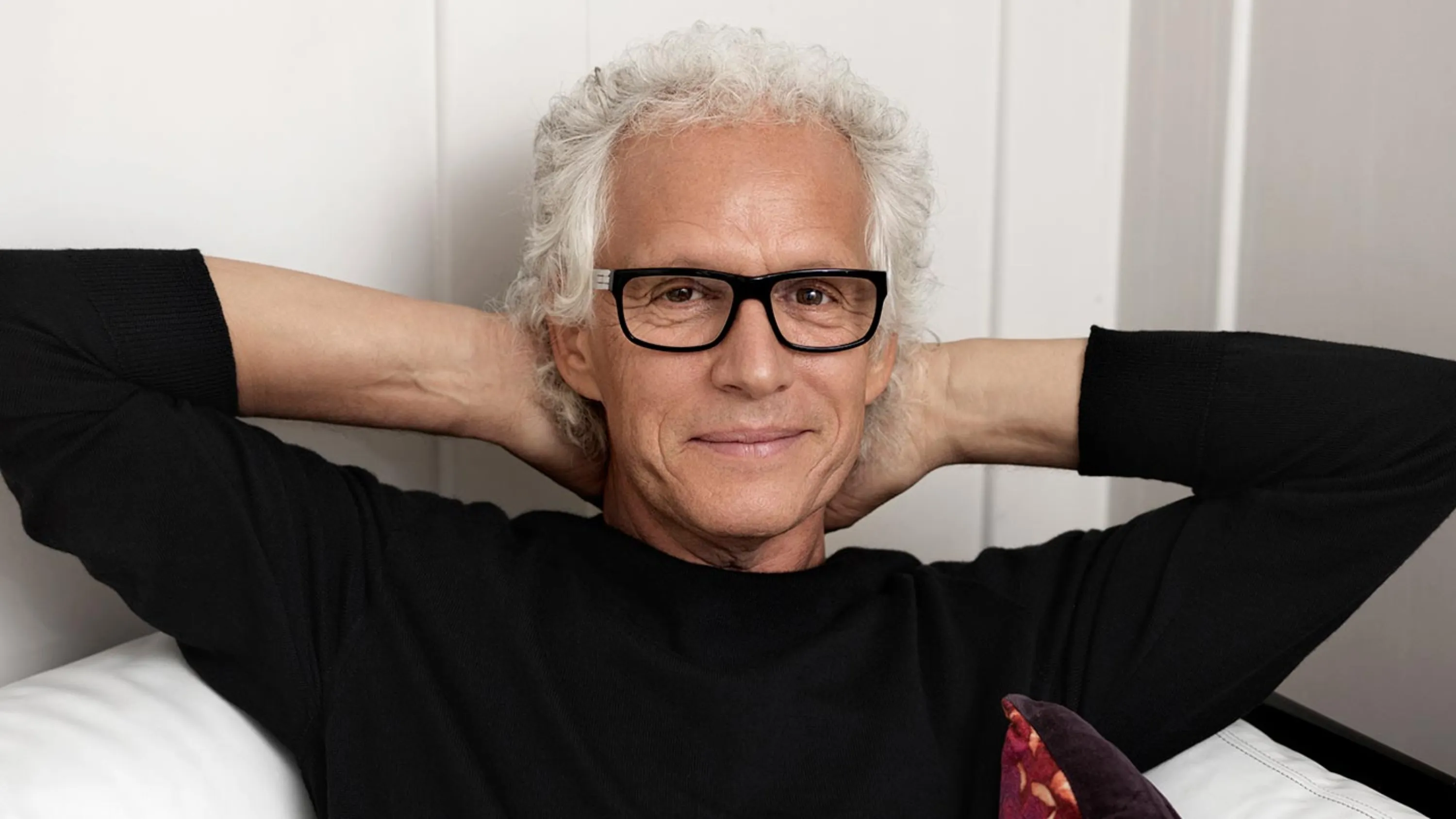 Grauhäriger Herr mit schwarzer Brille hält die Hände hinter dem Kopf und schaut dank der erhaltenen Rechtsberatung zufrieden.