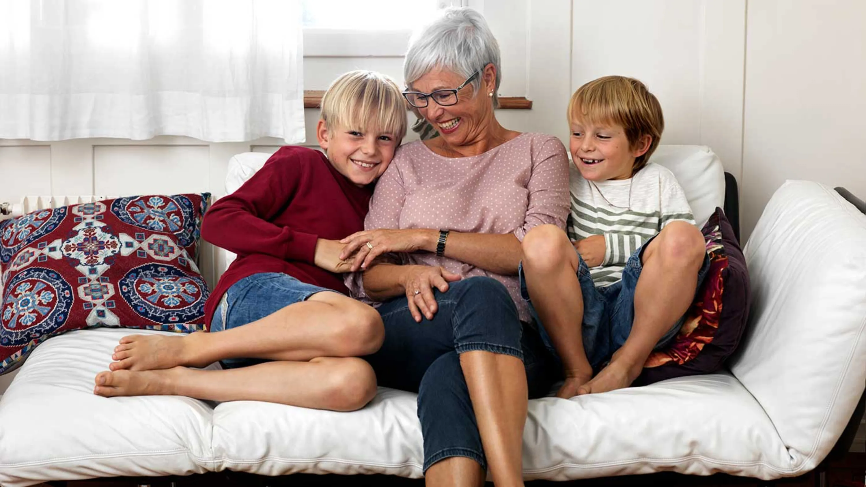 Grossmutter sitzt mit ihren Enkeln glücklich auf dem Sofa.