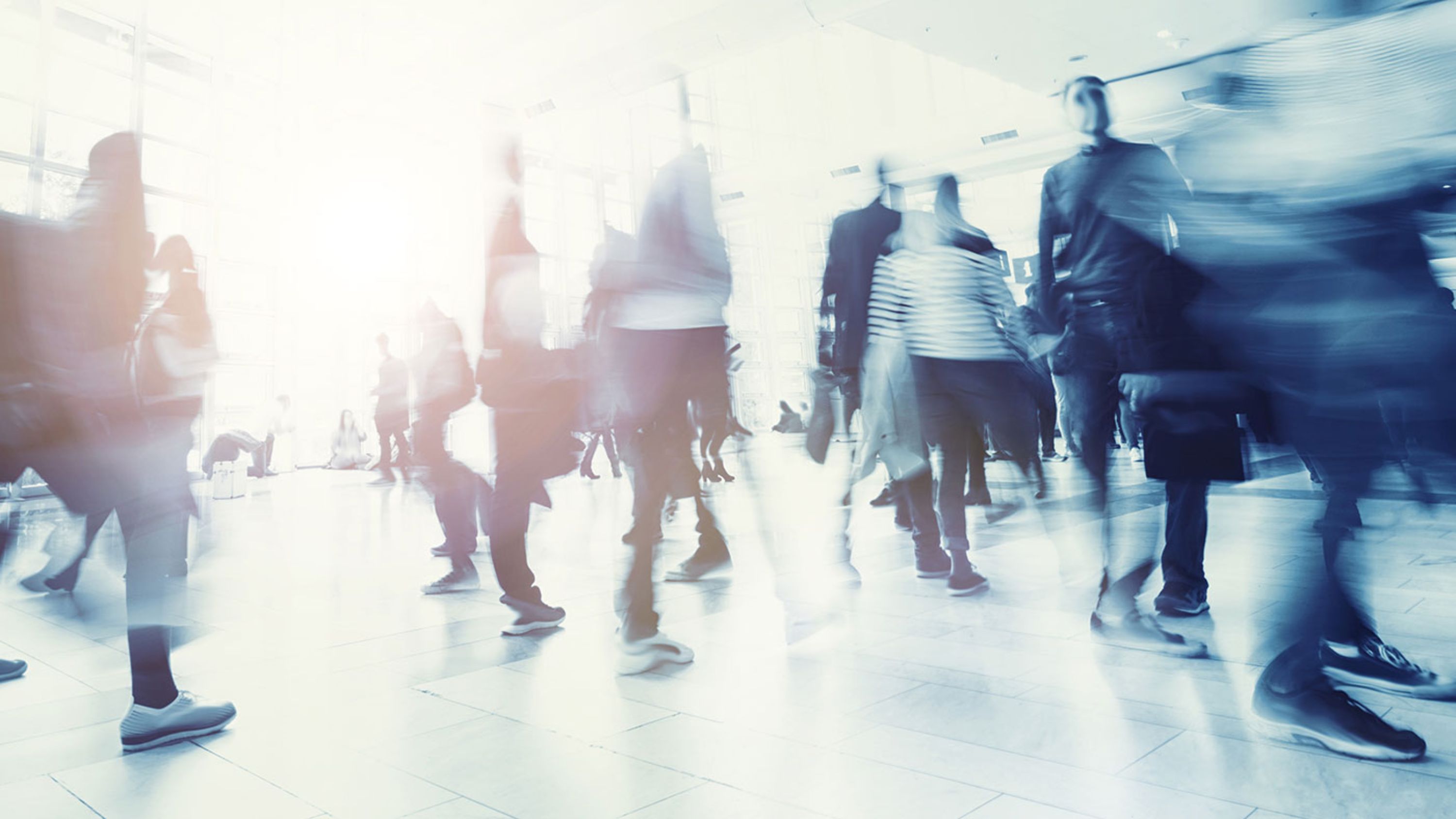 Schnappschuss von vielen Leuten, welche kreuz und quer durch eine Messehalle laufen.