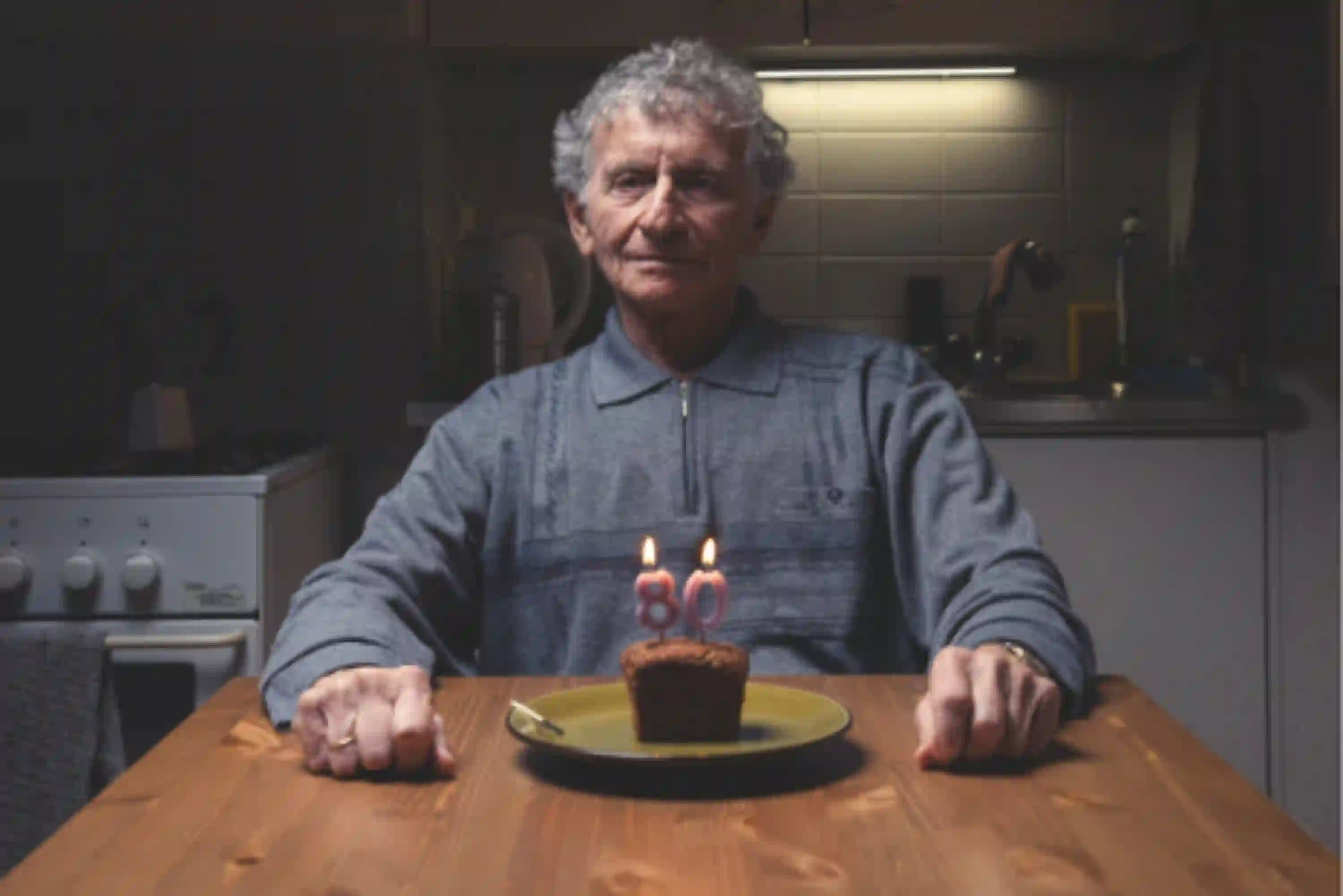 Einsamer Senior sitzt alleine an seinem Küchentisch und feiert seinen 80. Geburtstag