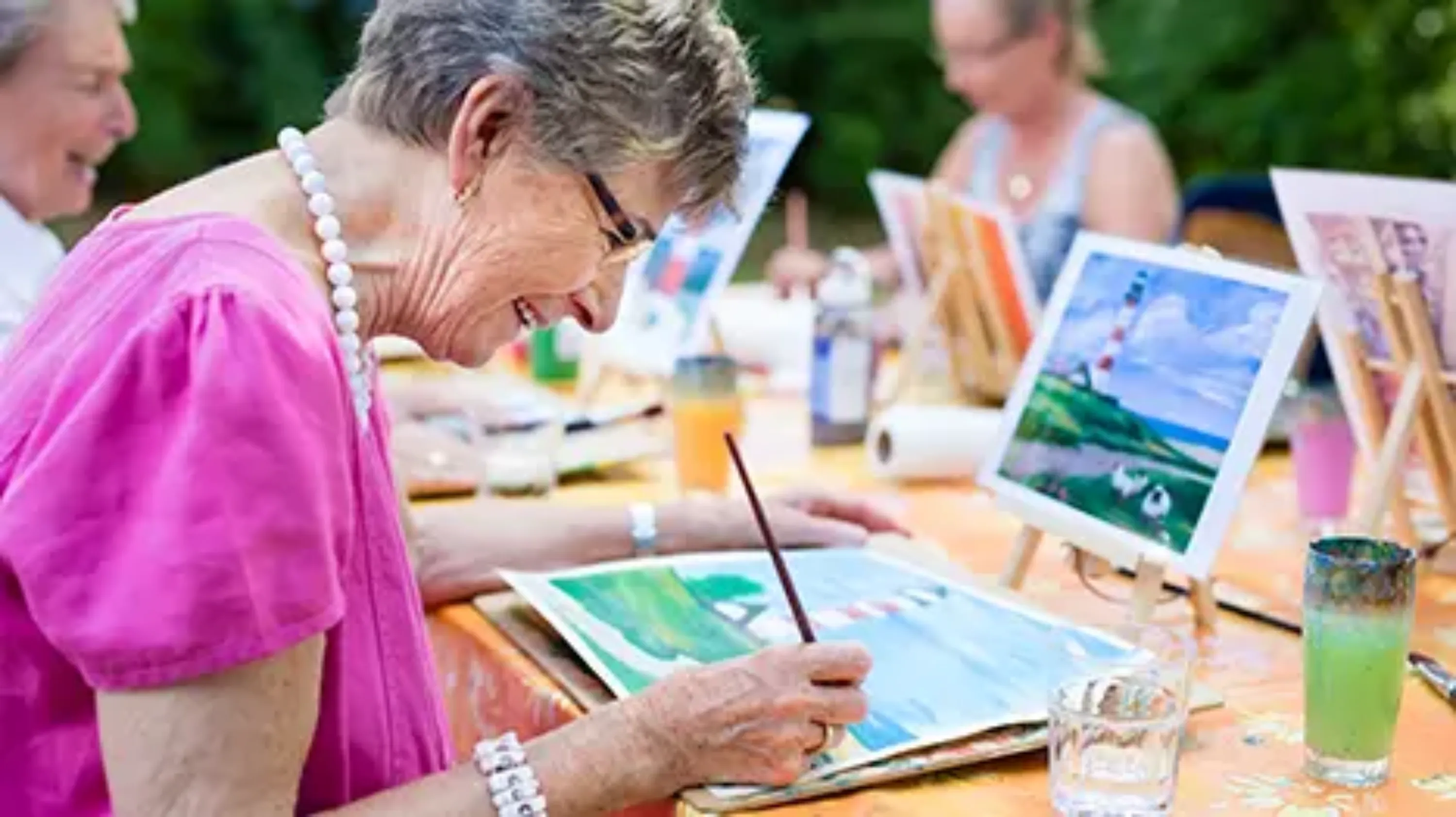 Groupe de personnes qui pratiquent la peinture sur une table en extérieur 