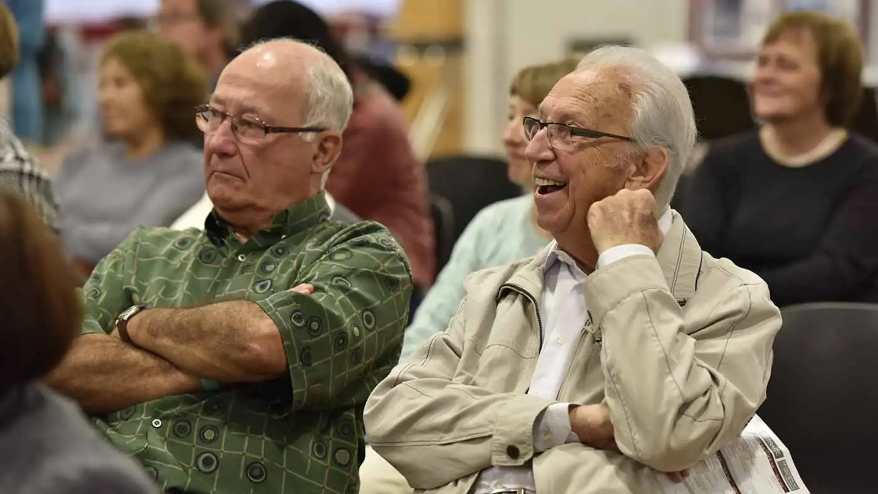 Deux hommes âgés, parmi un groupe de personne qui sont attentifs lors d'une conférence