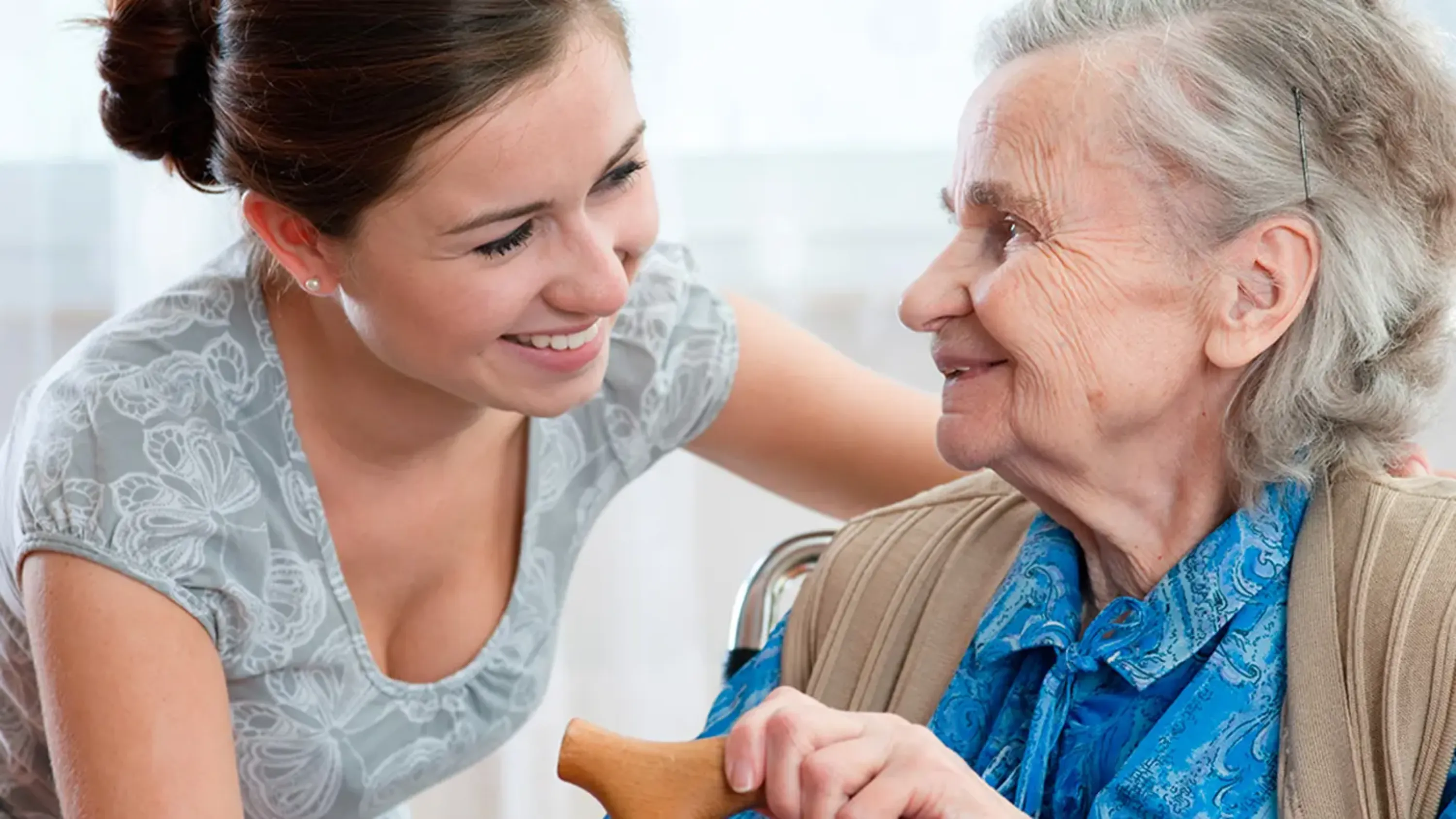 Une dame âgée et son accompagnante se sourient mutuellement