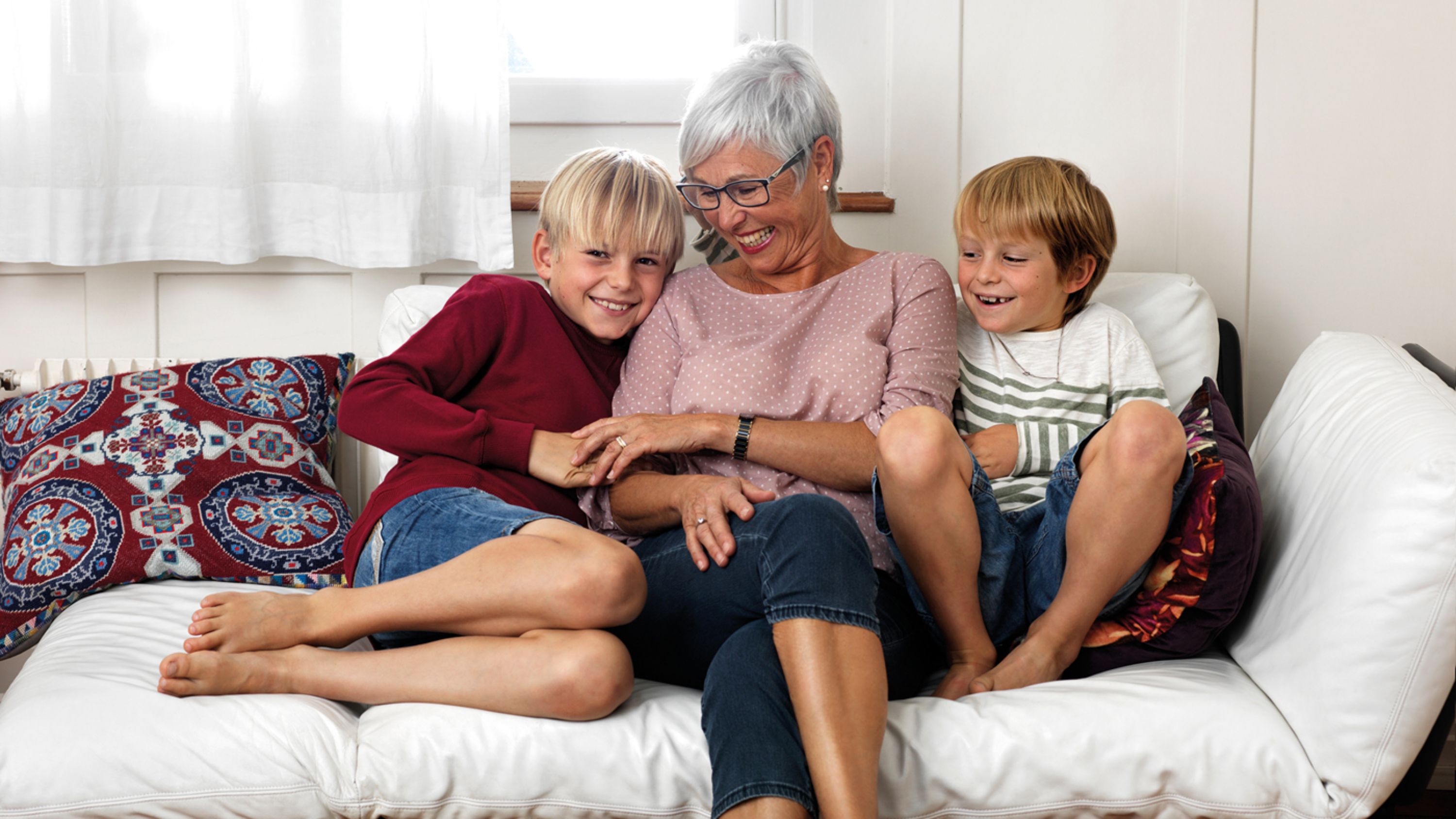 Une dame âgée et ses petits-enfants profitent du canapé. 