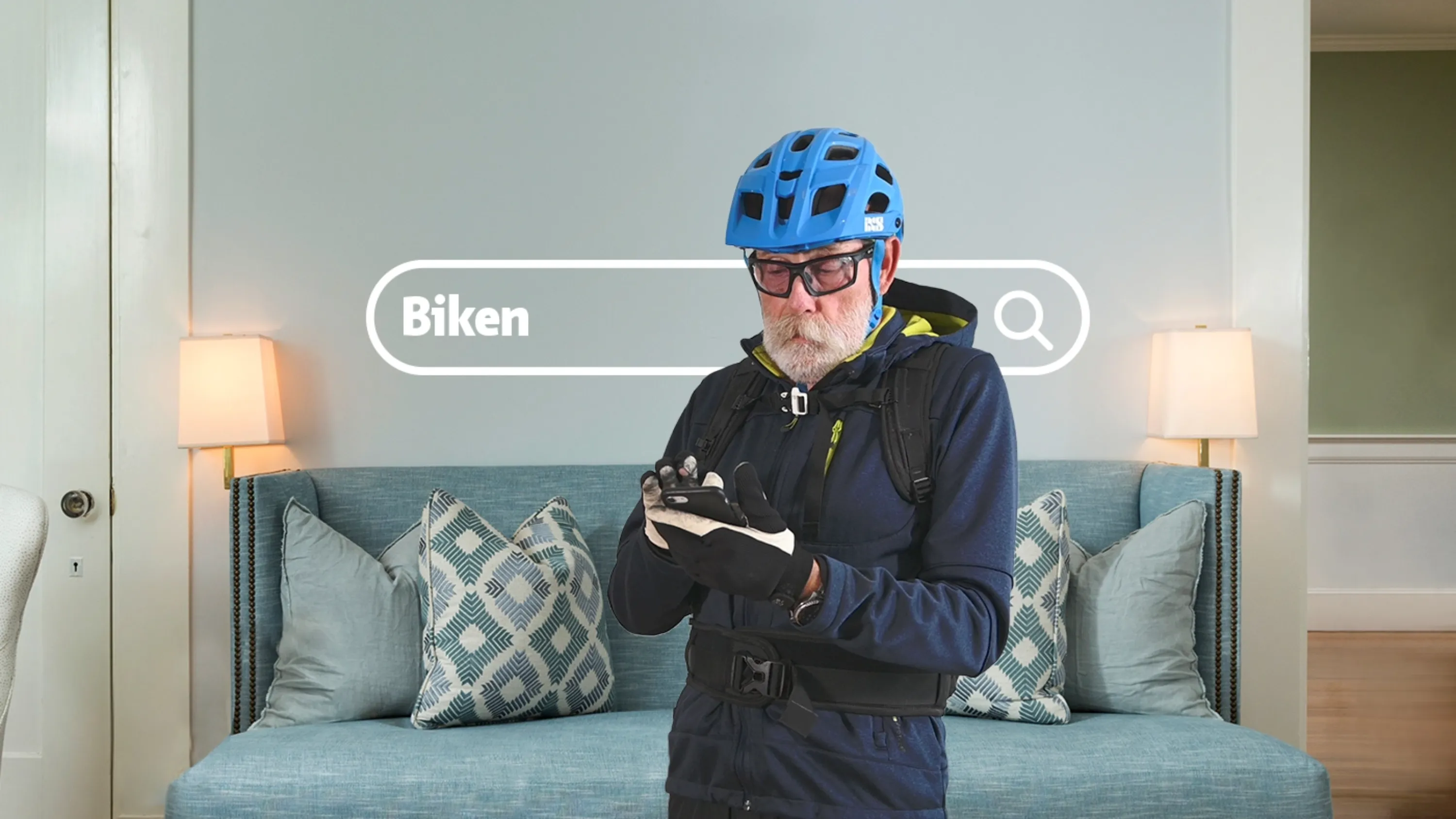 Ein Mann im Velo Outfit steht in seinem Wohnzimmer und plant seine nächsten Bikeausflug durch die Webseite von Pro Senectute.