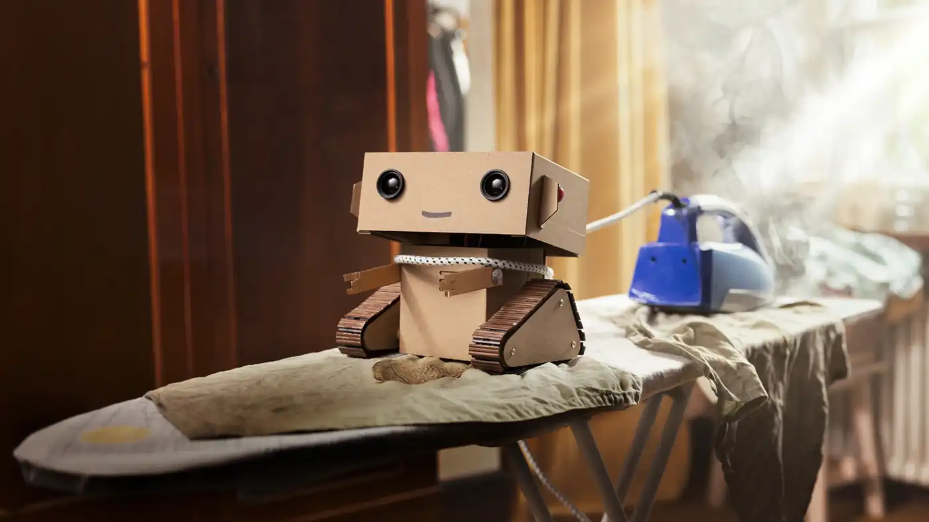 Der kleine Roboter Robi zieht ein dampfendes Bügeleisen auf dem Bügelbrett.