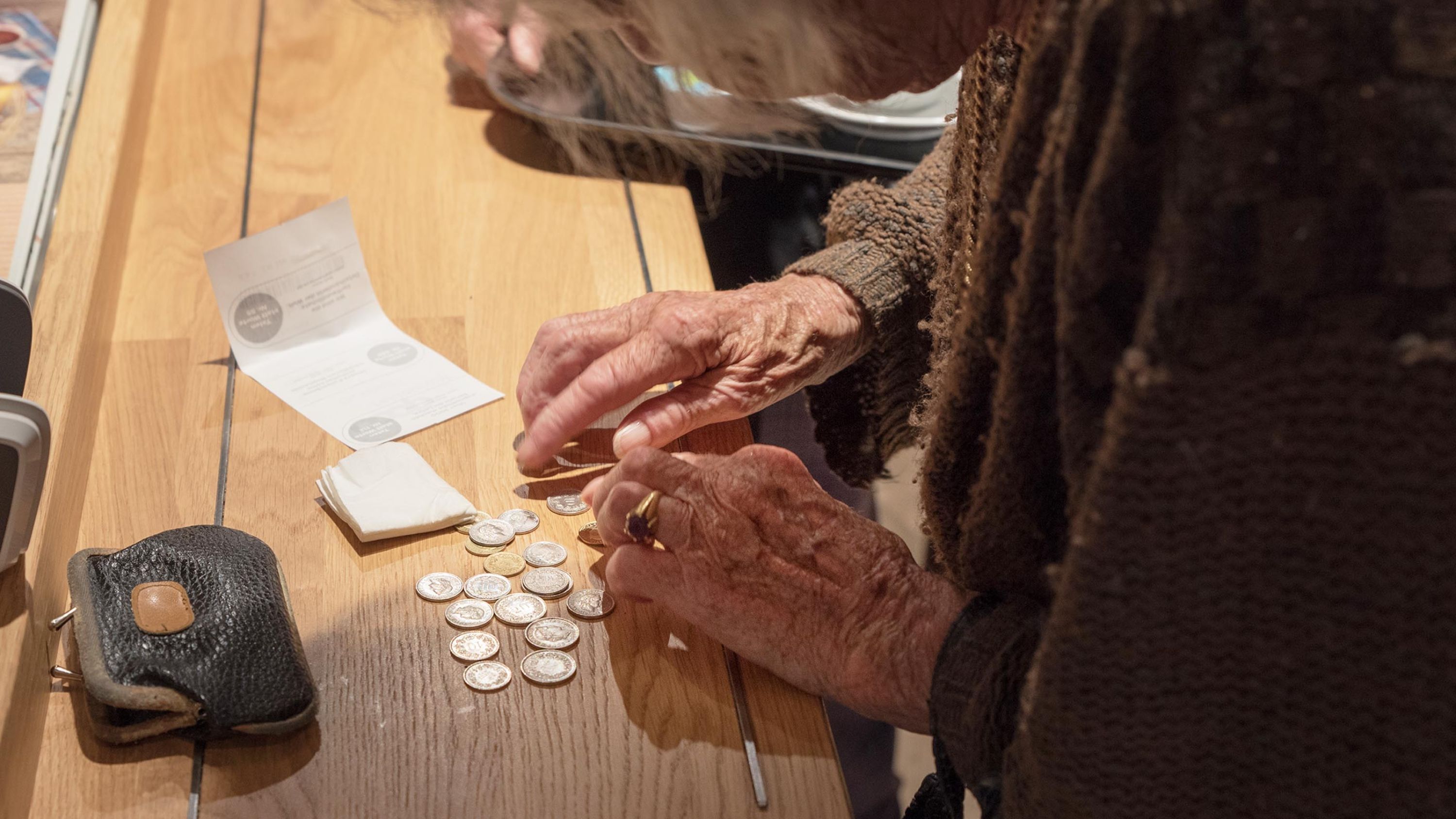 Eine arme Seniorin bezahlt mit vielen kleinen Münzen.