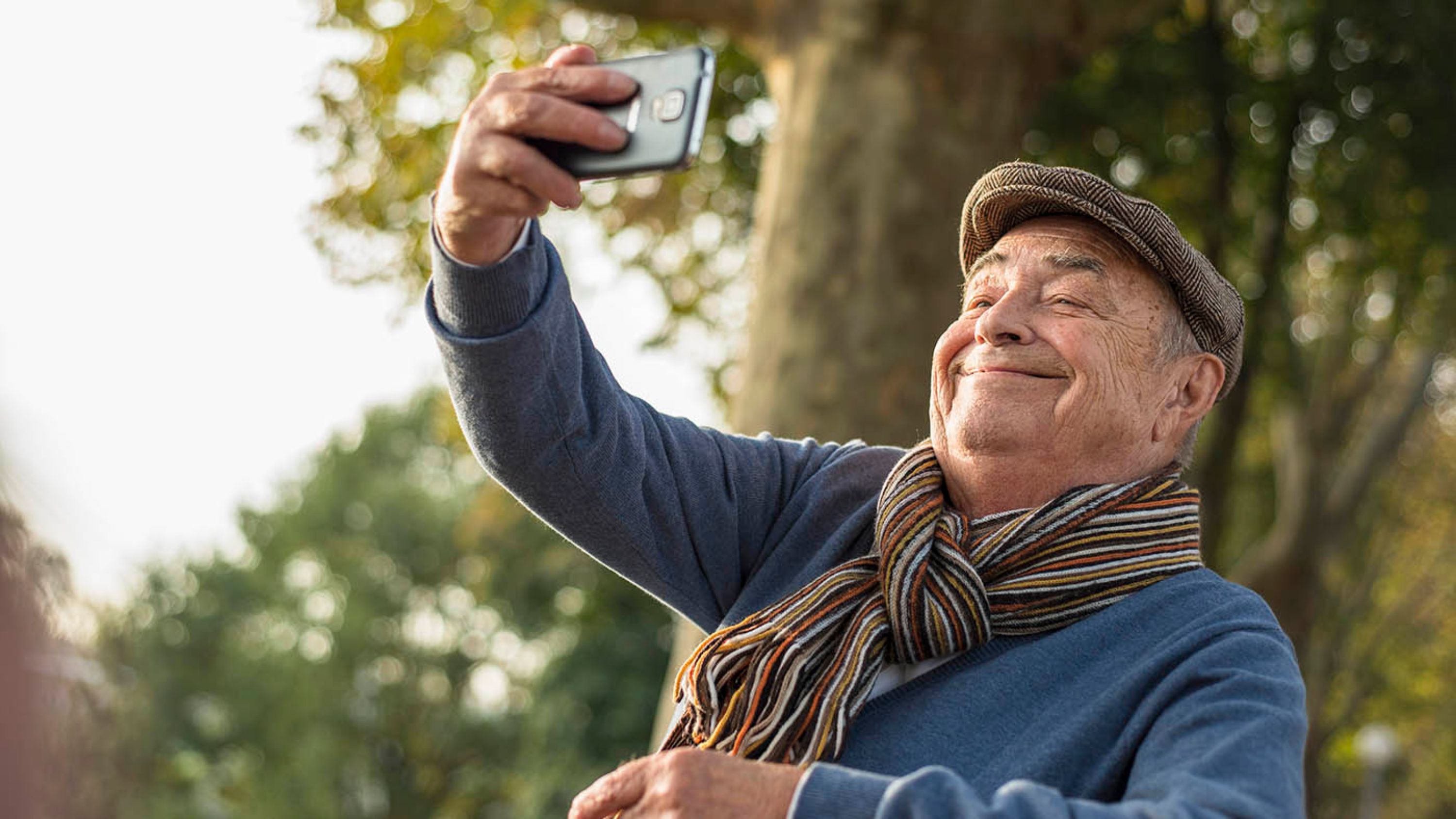 Un anziano si fa un selfie con lo smartphone.