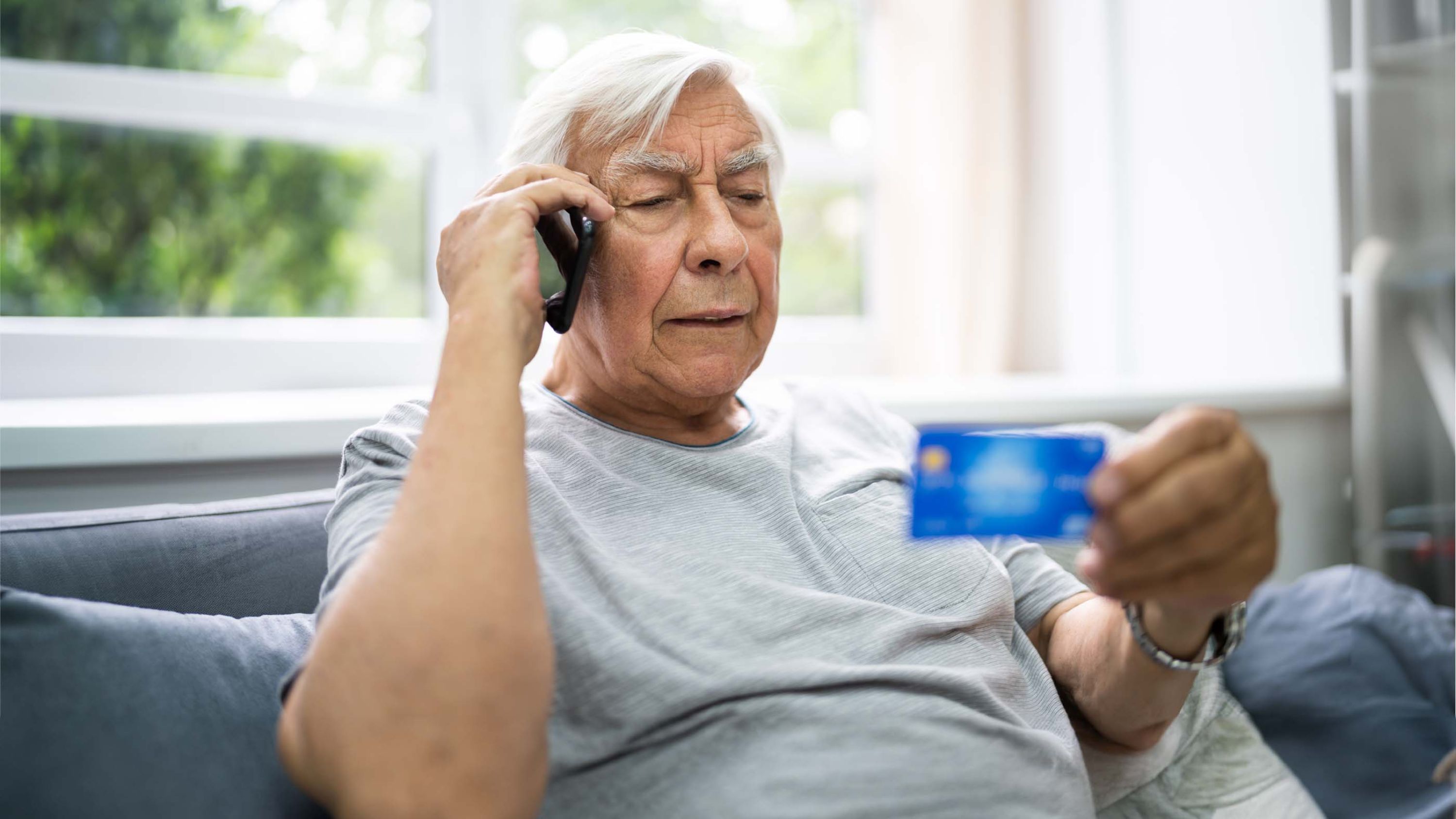 Un homme âgé au téléphone avec une carte de crédit