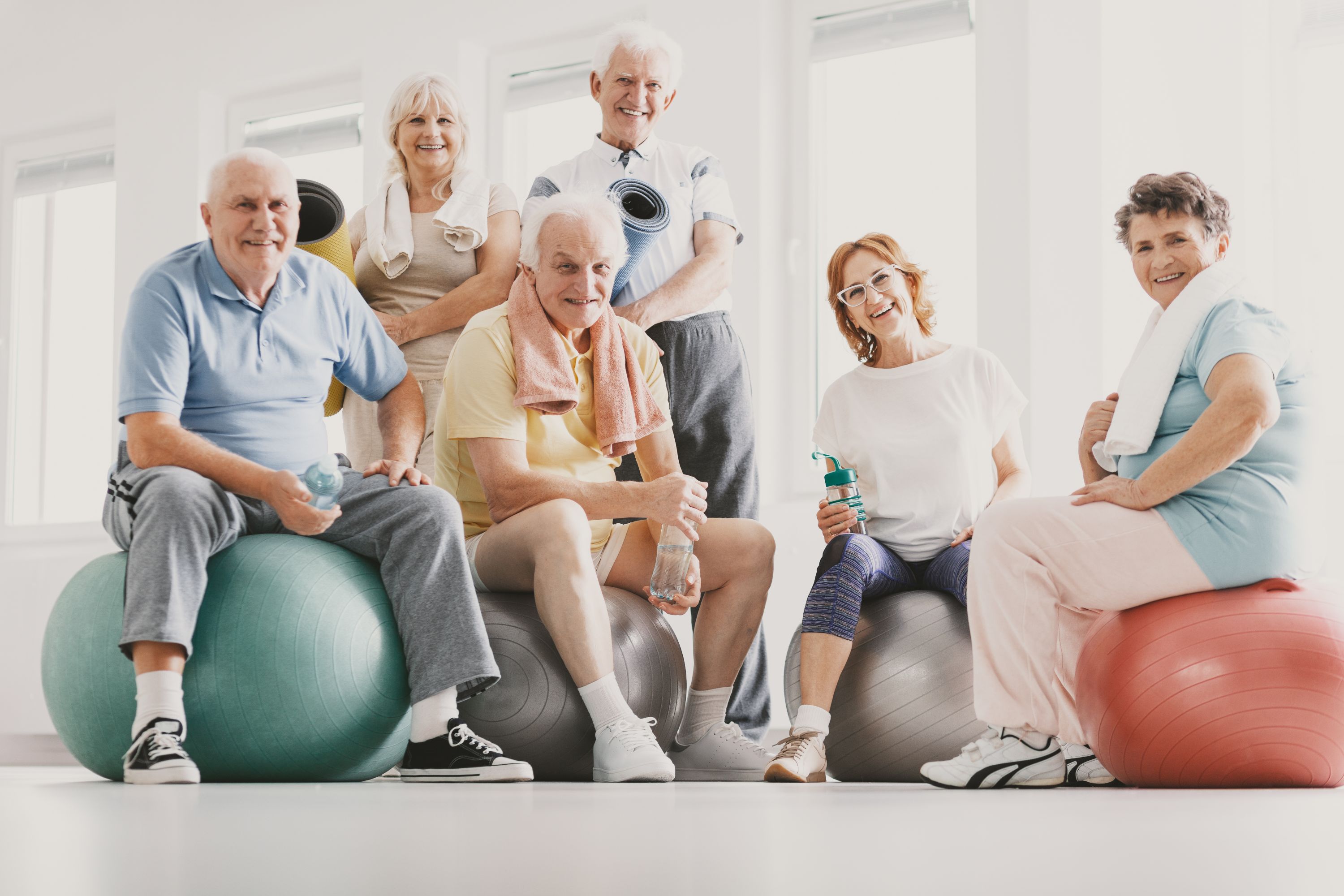 Gruppe von Seniorinnen und Senioren posieren auf Gymnastikbällen