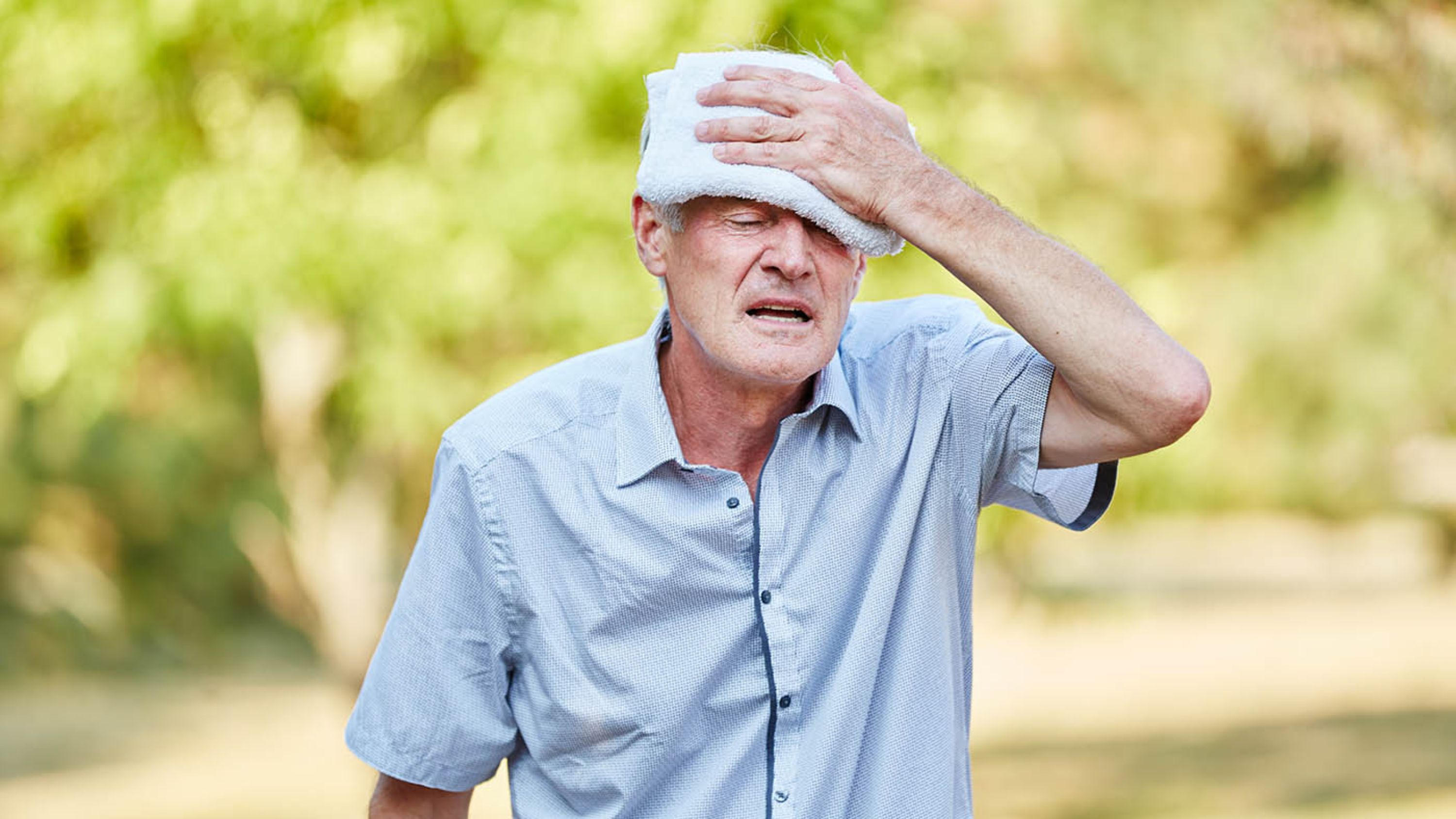 Ein älterer Mann legt sich ein nasses Tuch gegen die Hitze auf die Stirn.