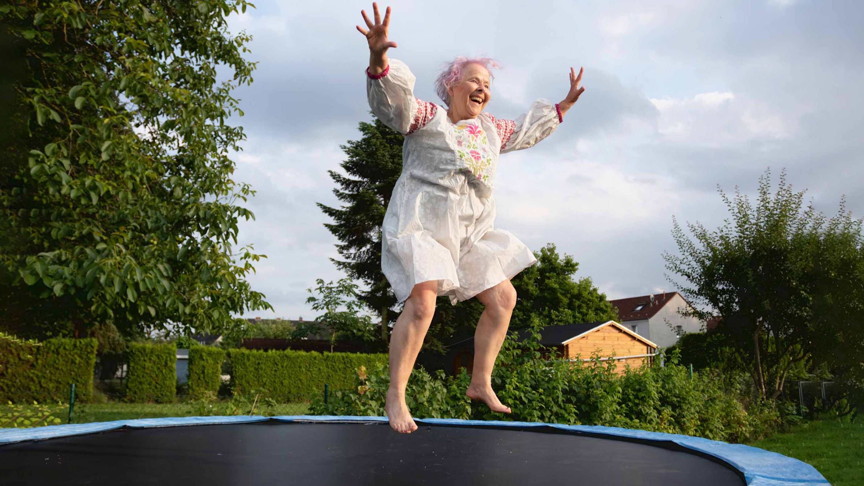 Une joyeuse dame âgée saute sur un trampoline.