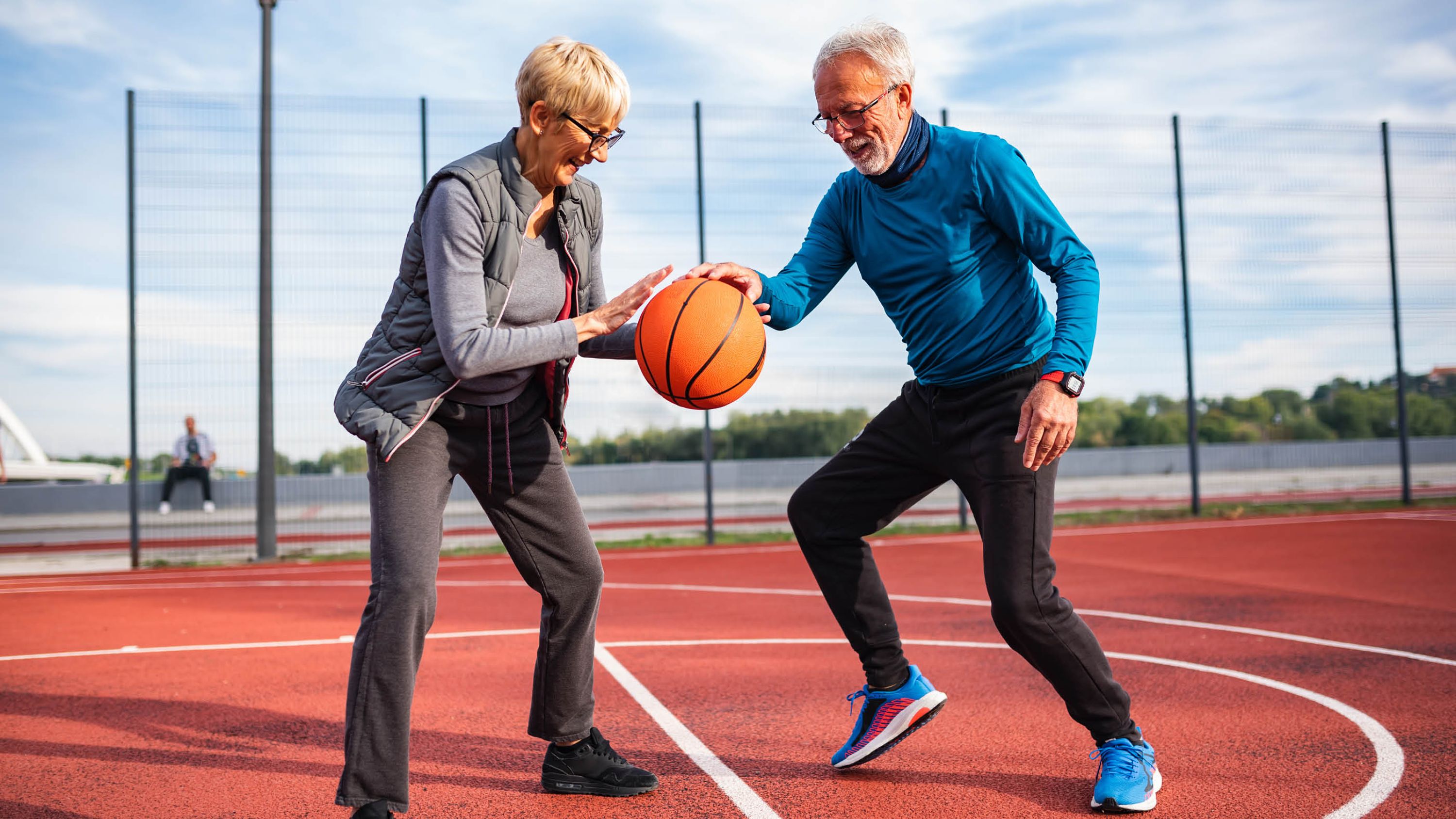 Zwei Senioren spielen zusammen Basketball.