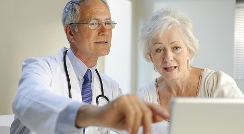 Arzt und Patientin diskutieren vor Laptop