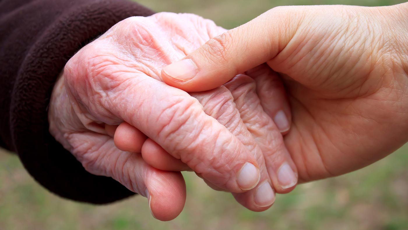 Eine junge Hand hält eine alte Hand.