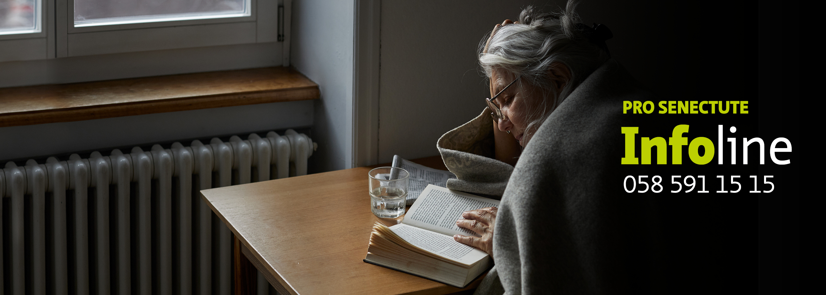 Une femme âgée avec une couverture lit un livre.