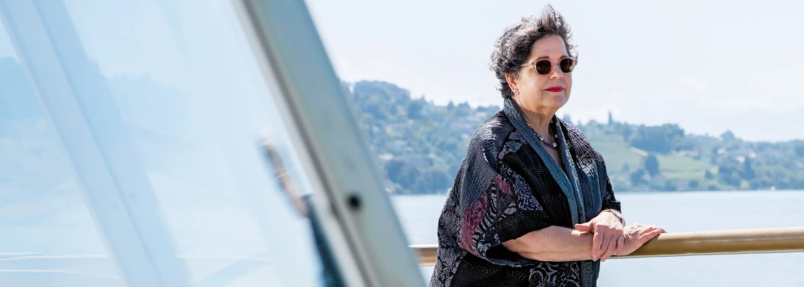 Eine Frau mit Sonnenbrille steht am Geländer auf einem Boot