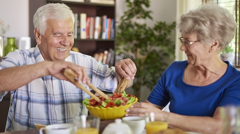 Ein älteres Paar: Sie hält die Salatschüssel, er schöpft sich Salat.