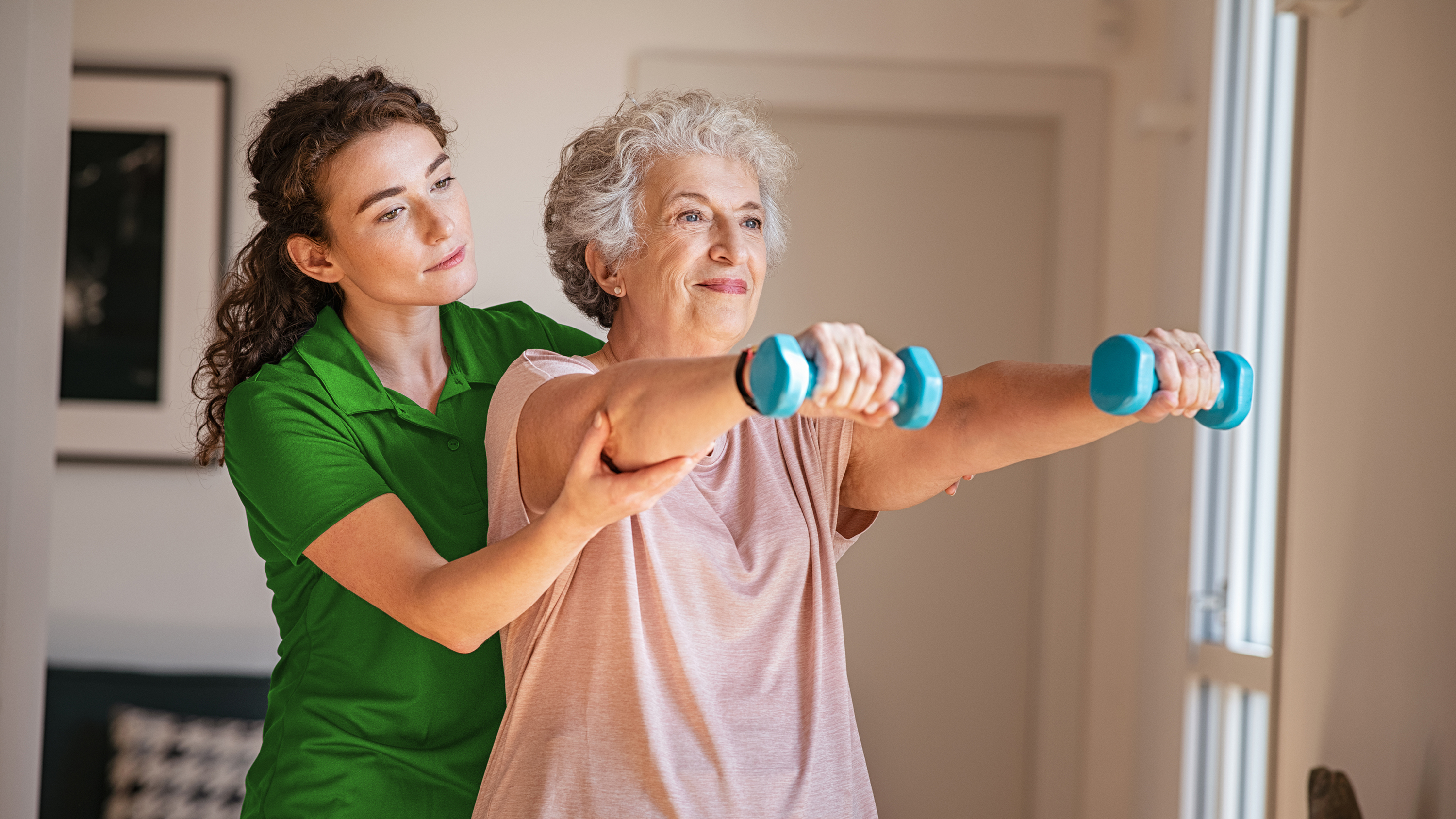 Eine Seniorin mit Hanteln trainiert mit ihrem DomiGym-Coach.