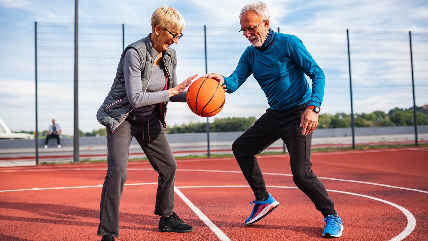 Una coppia di anziani gioca a basket.