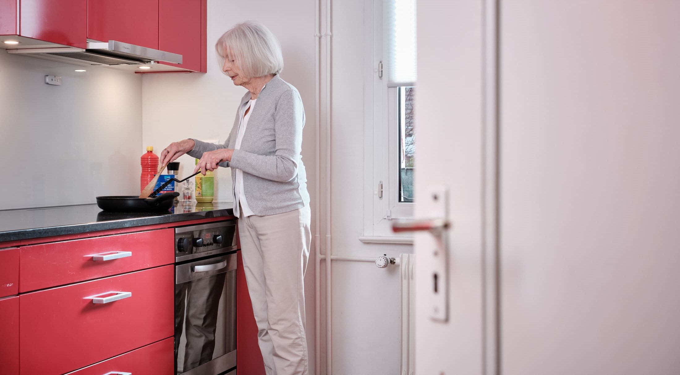 Signora anziana che cucina ai fornelli in cucina.