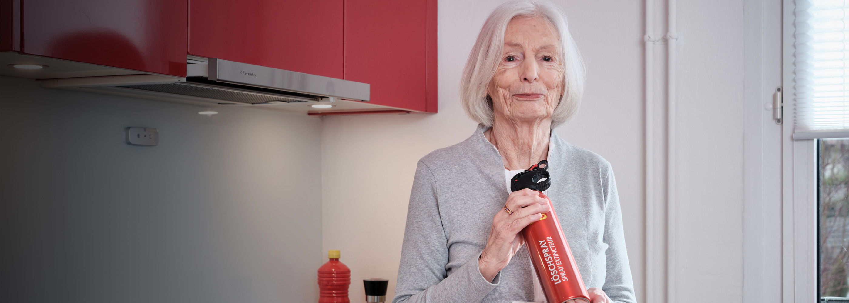 dame âgée avec un spray extincteur dans la cuisine