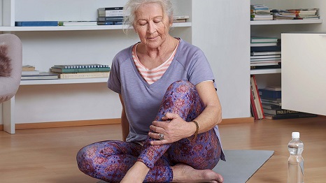Ältere Dame auf Yogamatte bei Dehnübungen 