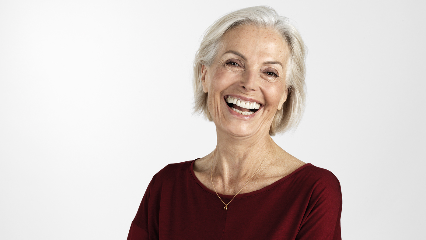 Un’anziana in camicetta rossa con un sorriso radioso.