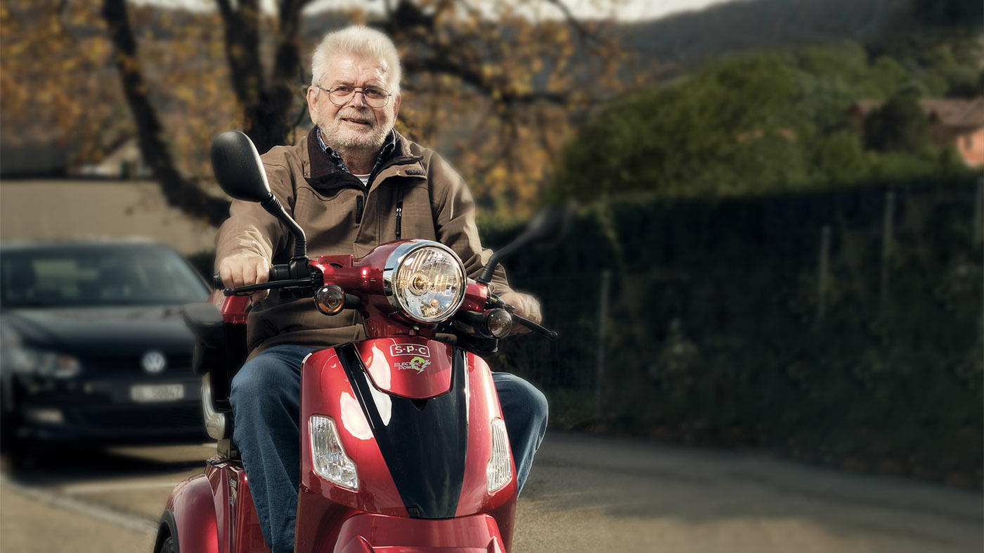 Joachim Hunsperger sitzt auf seinem roten Roller.