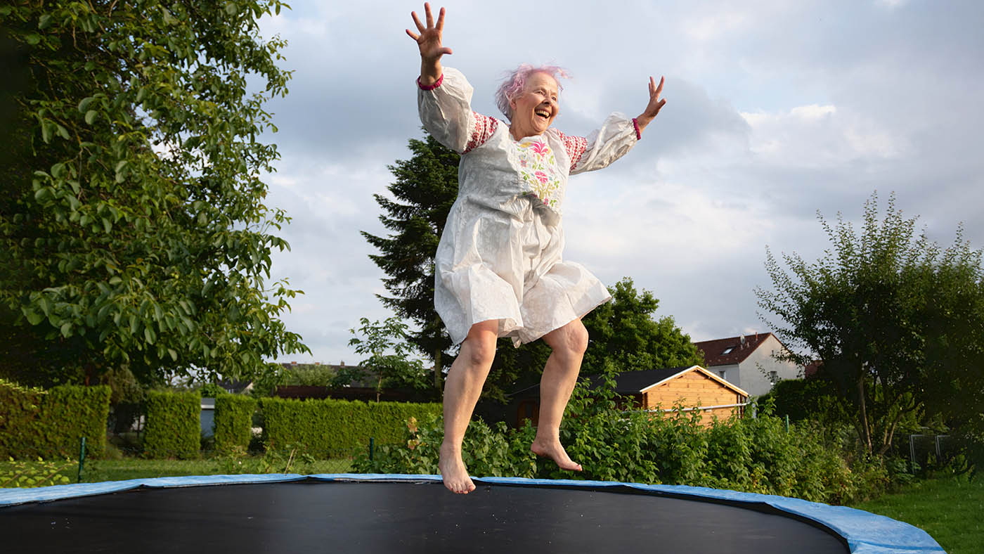 Fröhliche ältere Dame hüpft auf Trampolin.
