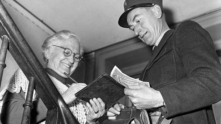 Un postino consegna a una pensionata il premio AVS, uno scatto dell’ottobre 1955  (foto Keystone-SDA/Jules Vogt).