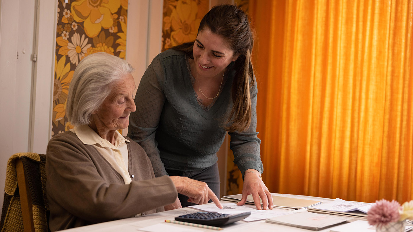 Un dipendente di Pro Senectute aiuta un cittadino anziano a svolgere lavori amministrativi. 